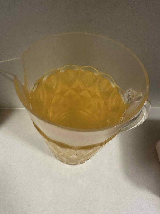 Bild på vattenkanna med gult, järnrikt vatten som visar missfärgning och utfällning trots filtrering.