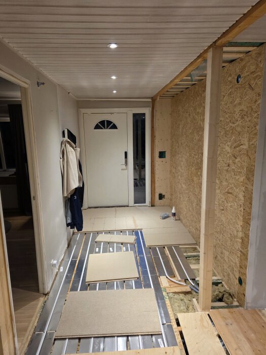 Renovering av hall med golvvärme, paneler mellan reglar, oinredd entré och monterade träväggar. Förbereds för klinker och parkettgolv.