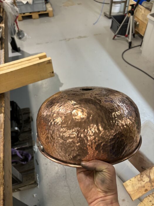 Bild av en hamrad och polerad kopparbunke som används för dekoration och isolering runt en skorstenspipa i byggprojekt.