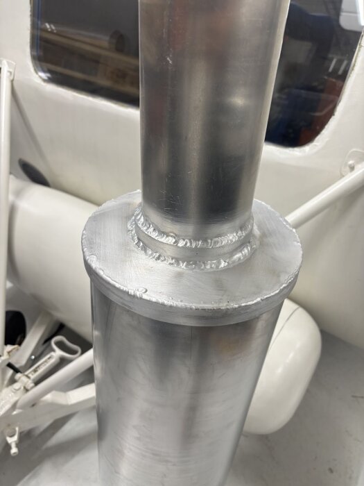 Aluminiumrör med tillhörande lock, svetsade fogar synliga. Del av skorstenskonstruktion för takgenomföring i byggprojekt, invändig vy.