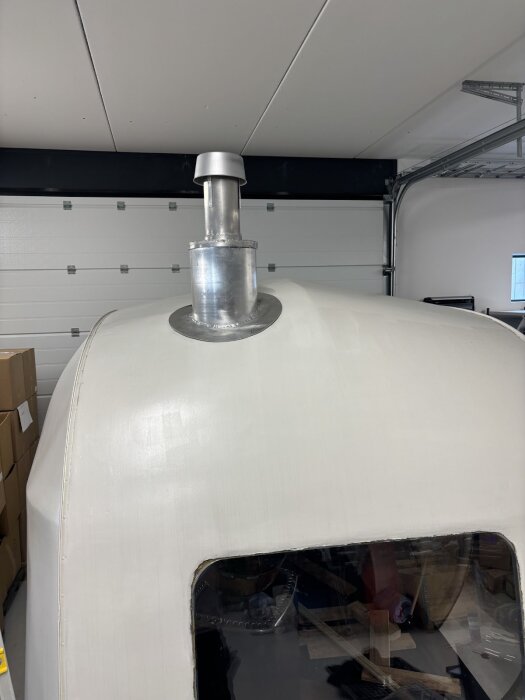 Regnhuv av kastrull monterad på skorsten, fastsatt på taket av en husbil i garage. Isolerad och målad för väderbeständighet.