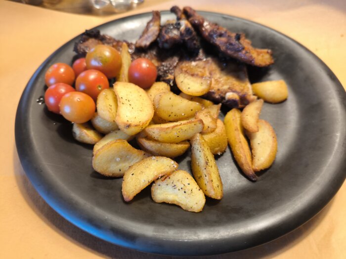 En tallrik med grillade kamben, körsbärstomater och ugnsrostade potatisklyftor.