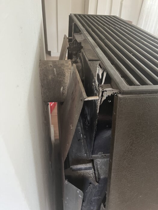Äldre kamin inbyggd i hål i väggen, visar sliten och skadad yta. Söker råd för att byta ut och installera ny kamin.