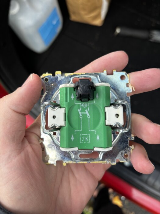 Brytare från hus byggt 1991, hålls i hand. Synliga elektriska kretsar och kontakter med grön bakgrund. Fotograferad för att visa trådarnas koppling.