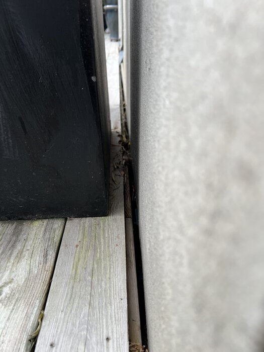 Mellanrum mellan putsad vägg och trädäck, där vatten kan tränga in. Sikt mot bas av vägg med luftningsutrymme.