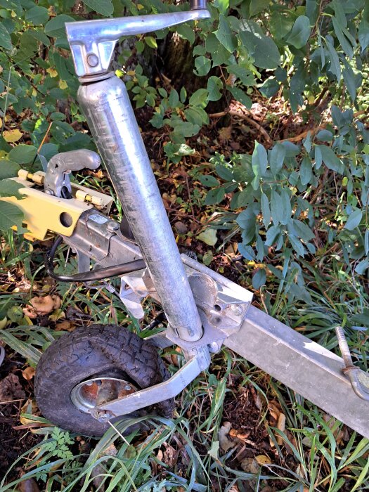 Stödhjul från Biltema monterat på en trailer, med ett handtag för justering och en robust konstruktion, omgivet av grönska.