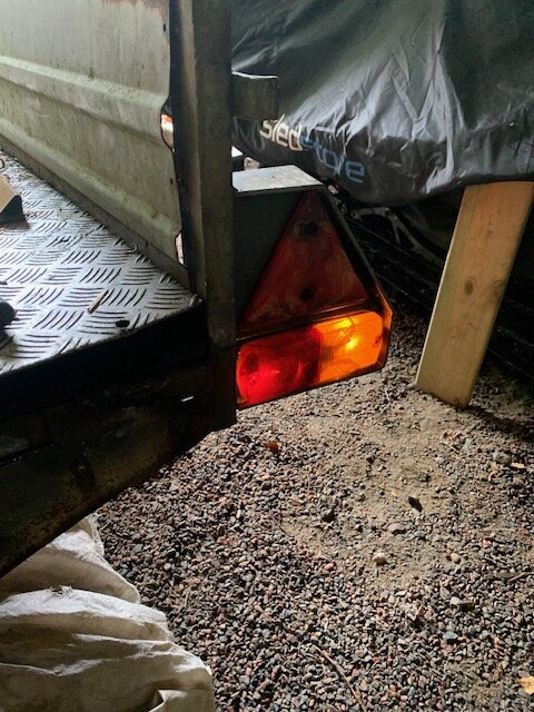 Baksidan av en släpkärra med trasig belysning; blinkande höger bakljus och blinkers syns tydligt.