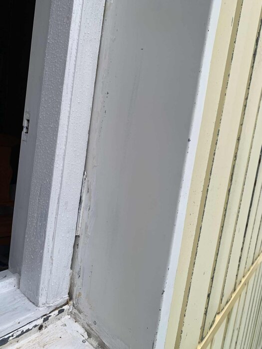 Fönsterkarm med fukt och flagande färg, utomhusmiljö.