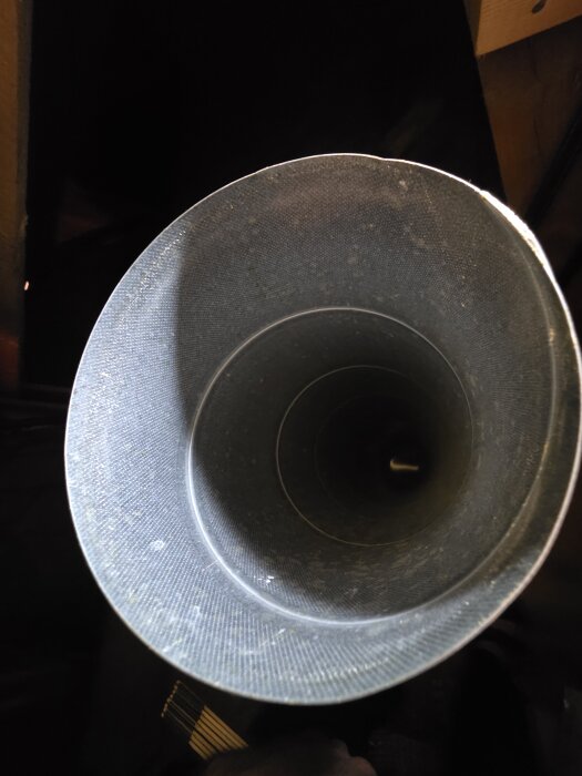 Närbild av änden på ett cirkulärt köksfläktsrör som har en grov yta och syftar till att kopplas till ett rektangulärt ventilationsutlopp.