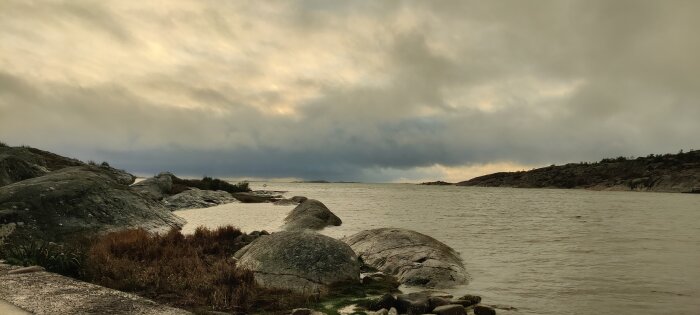 Kustlinje med klippor som vetter mot ett molnigt hav, med dyster himmel i bakgrunden.