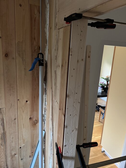 Dörröppning under förstoring med träreglar och limmad fiberboard, fastklämda med tvingar för att stärka strukturen på ena sidan av dörren.