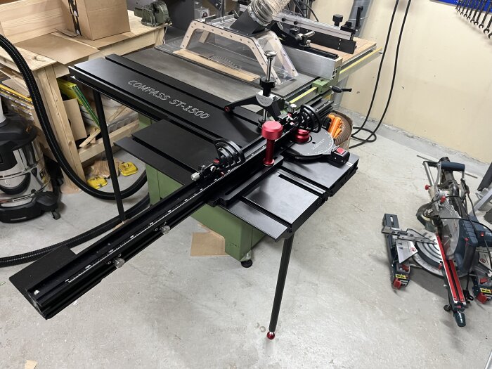 Justerbord för bordssåg, Compass ST-1500, installerat i verkstad med dammsugare och annan utrustning i närheten.