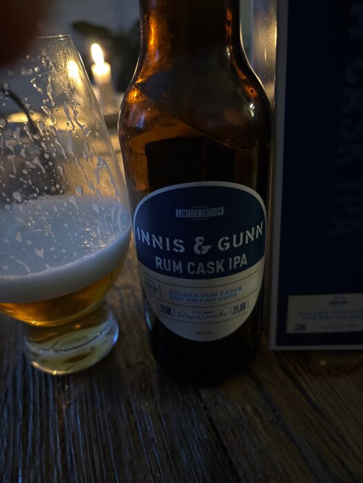 Flaska Innis & Gunn Rum Cask IPA och ett halvtomt ölglas på bord, skön belysning.