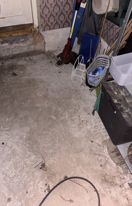 Gjutet betonggolv under trägolv, omgärdat av olika verktyg och föremål, del av renoveringsprojekt.