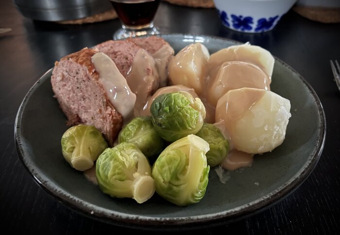 Tallrik med köttfärslimpa med brunsås, kokt potatis och brysselkål.