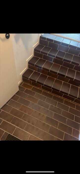 Bruna Höganäsklinker plattor i en hall, mönstrade som tegel, både på golv och steg; sökes fler för renovering av 1960-talshem.