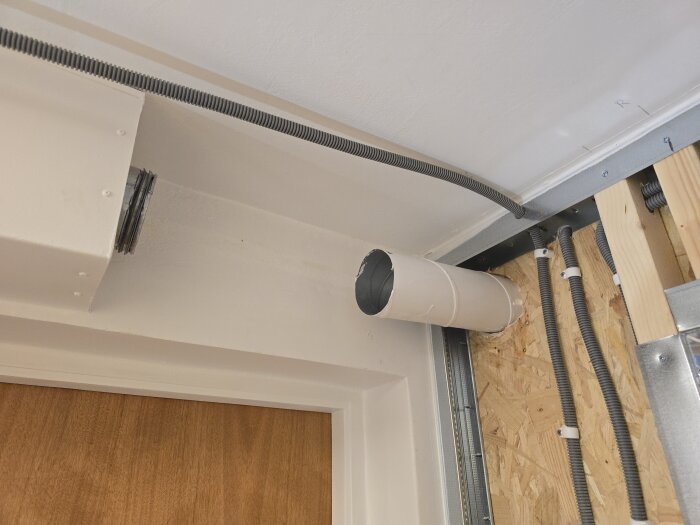 Ventilationsrör och flexrör installerade i vägg med OSB-skiva samt trä- och metallramverk.