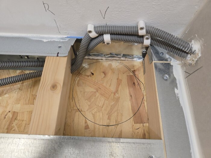 Flexrör och markering för hål i OSB-skiva, förberett för installation av ventilationskanal med spirorör i ett byggprojekt.