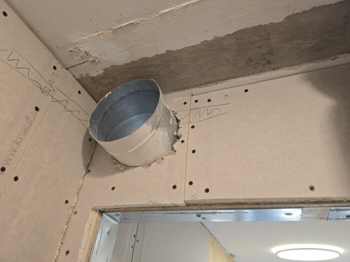 Hål för spirorör genom gips och OSB-platta, med borrade hål runt kanten samt rördragning för ventilation.