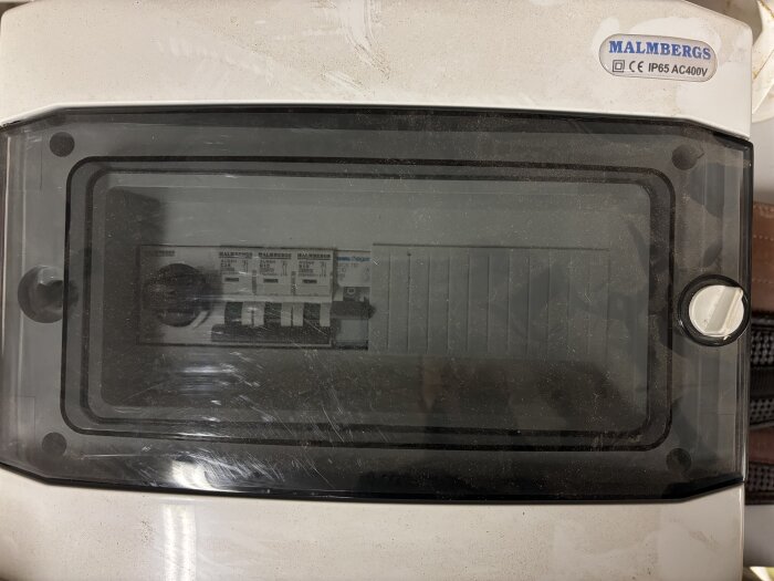 Normcentral med synliga dvärgbrytare från Malmbergs, IP65 AC400V, monterad i en vit kapsling med transparent lock.