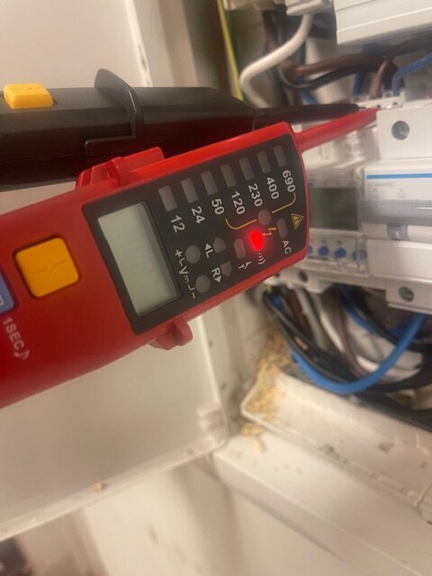 Multimeter mäter spänning mellan L och N i en elbox, visar 230V.