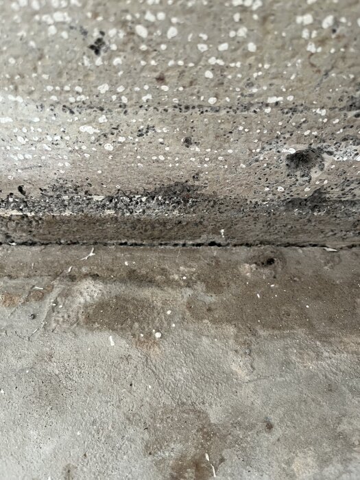 Spricka mellan betonggolv och vägg upptäckt vid golvbyte, med ojämn fuktighetsnivå som diskussionstråden handlar om att åtgärda med tätning.