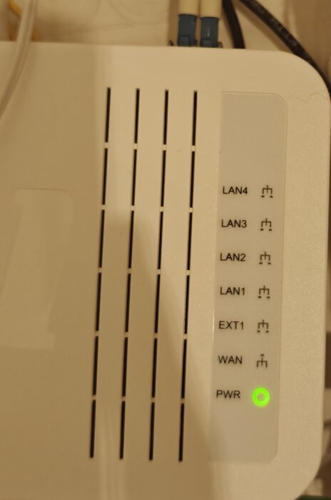 Vit mediasplitter med LAN- och PWR-indikatorer, grönt ljus vid PWR, kopplingskablar ovan.