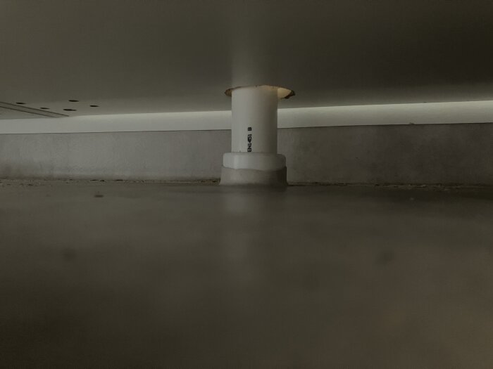 Rörgenomföring för spillvatten från handfat med våtrumsmatta uppvikt runt donuten, cirka 1 cm upp, belägen över 6 cm från väggen.