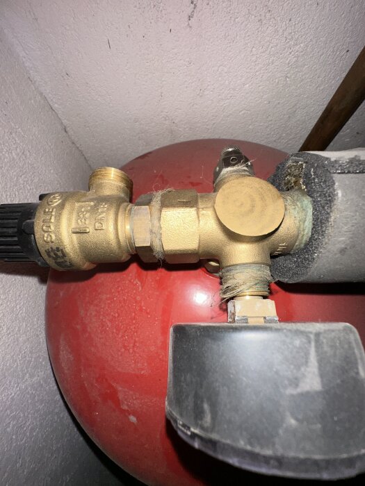 Ventil och röranslutningar på en röd expansionsbehållare i ett pumprum, del av en Nibe Fighter 1225 värmepump.