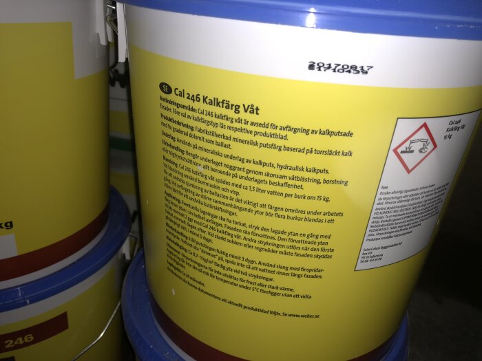 Gul hink med Weber Cal 246 kalkfärg, använd för målning av kalkputsade väggar, detaljerad text om produktens egenskaper och säkerhetsinstruktioner.