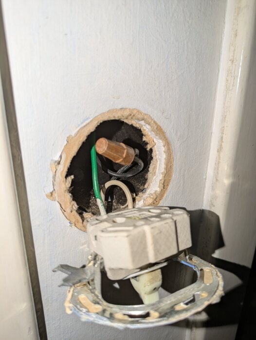 Gammal eluttag med synliga kablar och skadad vägg, förberett för ny strömbrytare.