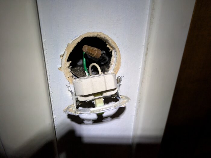 Öppen väggdosa med gamla elkomponenter och synliga kablar från 1961, förberett för installation av en ny strömbrytare.