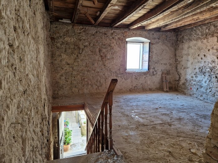 Rivet rum med murade väggar, träbalkar i taket och en öppen trappa, sett i juni efter att ha påbörjat rivningsarbetet i april.