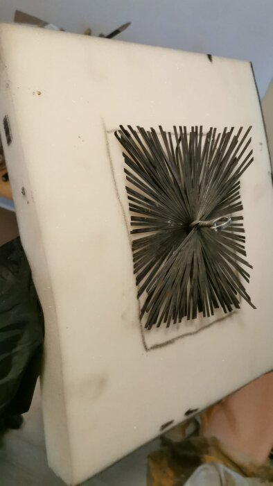 Rektangulär skumplatta med borste i mitten, del av rensutrustning för skorsten.