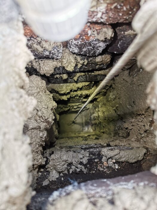 View inside a chimney showing mortar layers on brick walls after cleaning and mortar application. A cable is visible, used for pulling the cushion.