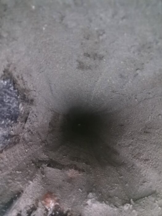 Insidan av rökkanalen på en skorsten, belagd med ett lager murbruk mellan tegelstenarna efter rengöring och applicering av murbruk.