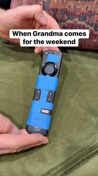 Fjärrkontroll täckt med blå tejp på knappar, hålls av en hand, och texten "When Grandma comes for the weekend" syns ovanför.