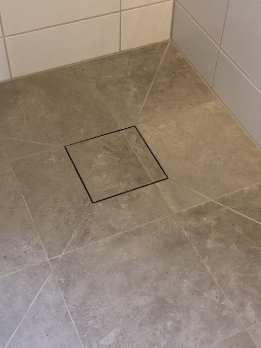 Grått klinkergolv med fyrkantig golvbrunn.