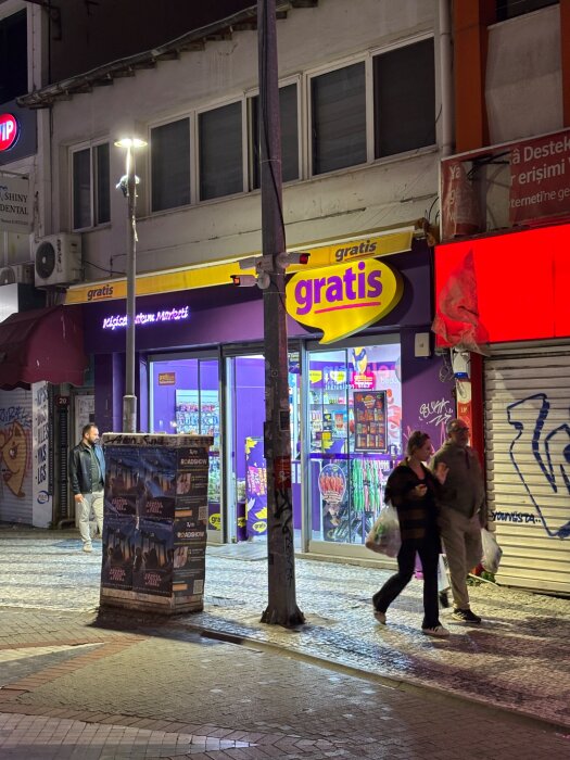 Folk går förbi en butik med en färgglad skylt med texten "gratis" synlig.