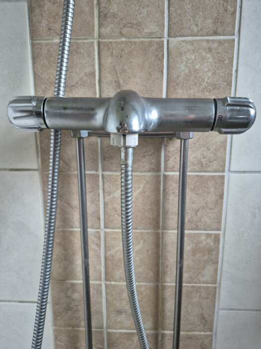 Termostatblandare med omkastare för badkar och dusch, på vägg med beige kakel. Fråga om hur omkastaren lossas.