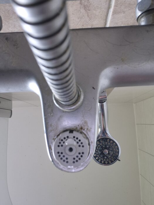 Duschkran och omkastare med ansluten slang, fokus på omkastaren som verkar sitta fast.