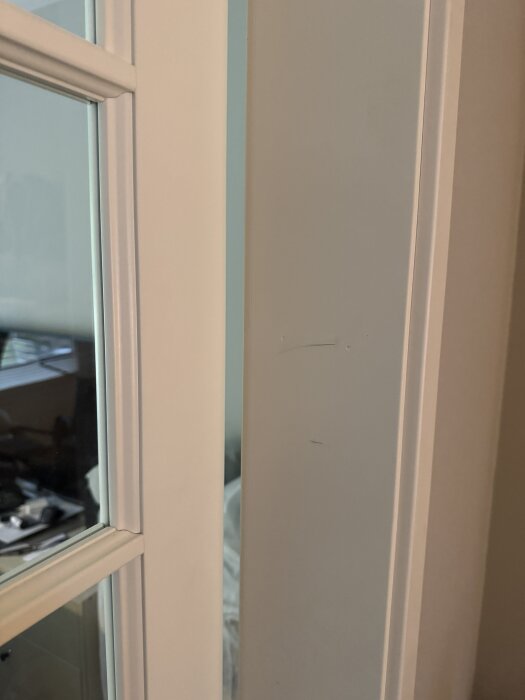 Dörrkarm med vita lister och glasdel, synlig inre del av dörröppning.