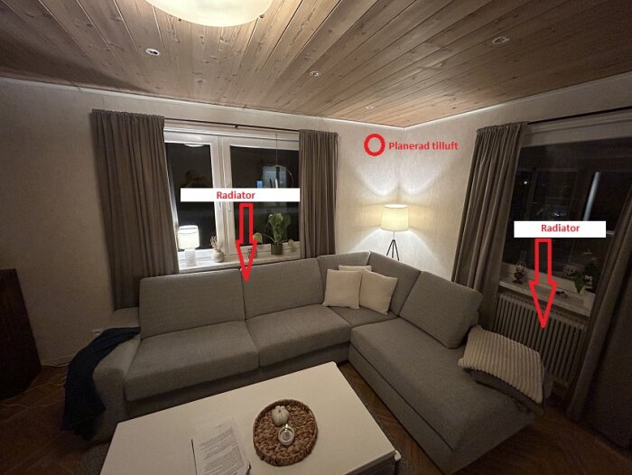 Bild på vardagsrum med grå hörnsoffa, lampor vid fönster och markering av planerad tilluftsventil samt radiatorer under fönstren.