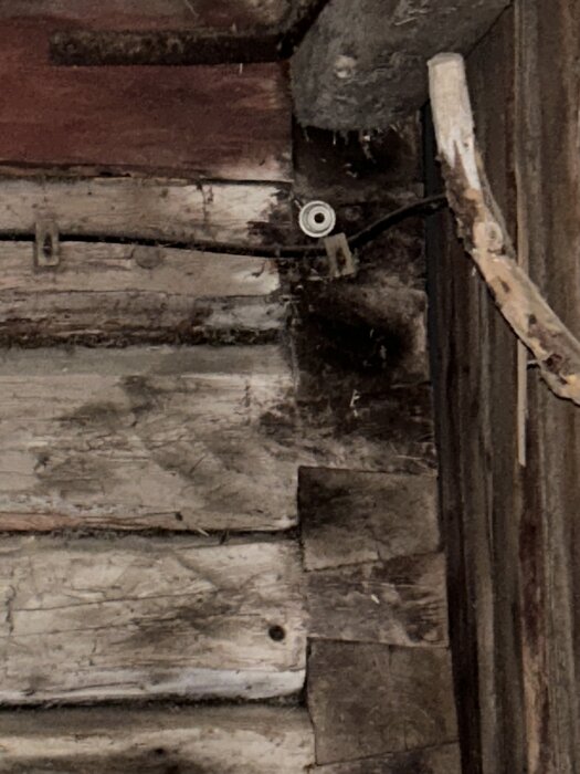 Gammalt timmerhus med slitna stockar och trädetaljer, del av ett tidigare stall.