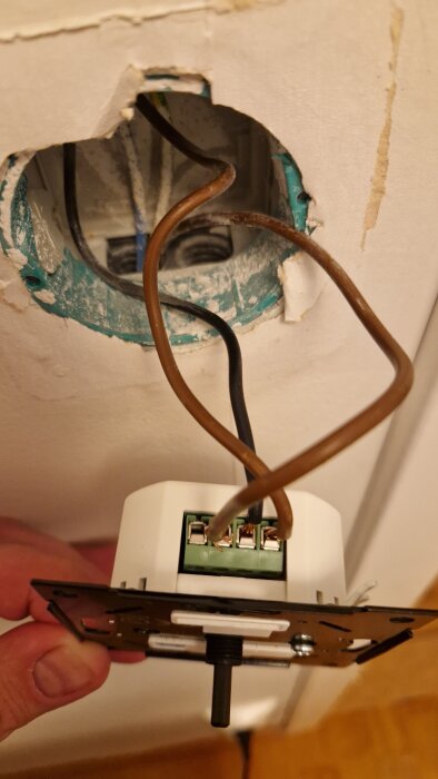 Elektrisk dosa med synliga koppartrådar, vägguttag utanför väggen.