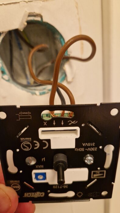 Installationsprocess av en dimmer med sladdar synliga i en elbox, redo för anslutning.