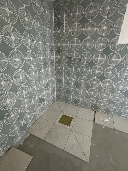 Kakelvägg och klinkergolv med mönster i ett badrum, med precisa och jämna snitt runt en golvbrunn.