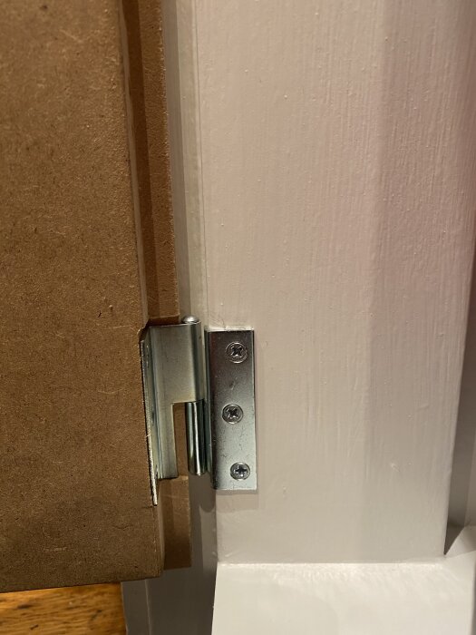 Gångjärn monterat med försänkta skruvar i en dörrfals, visar exakt fräsdjup för att eliminera glipor mellan lucka och stomme.