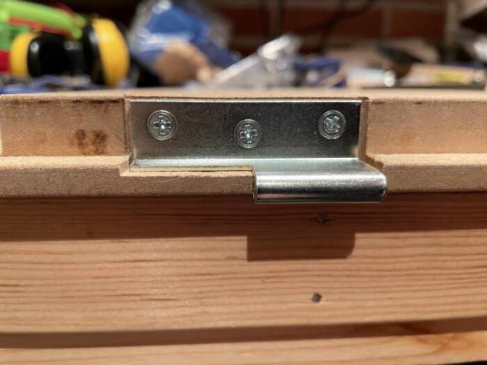 Gångjärn monterat i en försänkt urgröpning på en trädörr, fastsatt med tre försänkta skruvar.