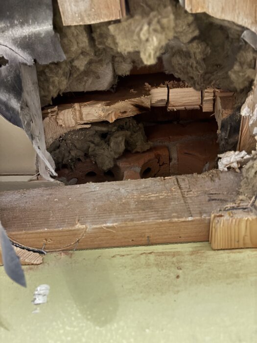 Utskuren takstol med synlig isolering och tegel efter borrning för ventilation i ett husprojekt.